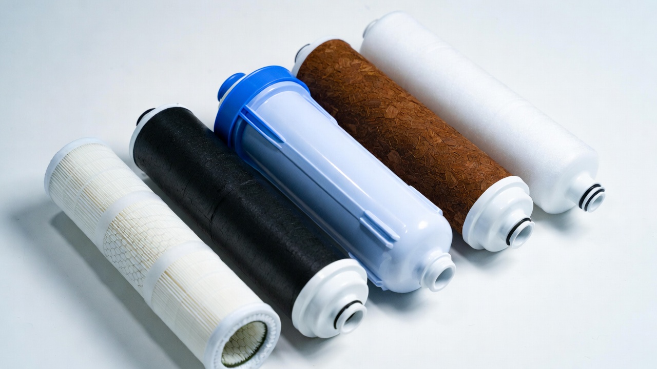 Five reverse osmosis replacement filter cartridges arranged in a row — sediment, carbon block, RO membrane, post-carbon polish, and coconut shell carbon